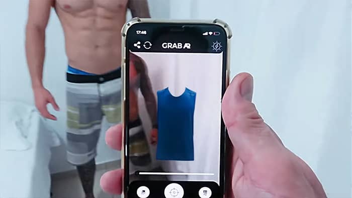 Homem sendo fotografado por celular com imagem de camiseta